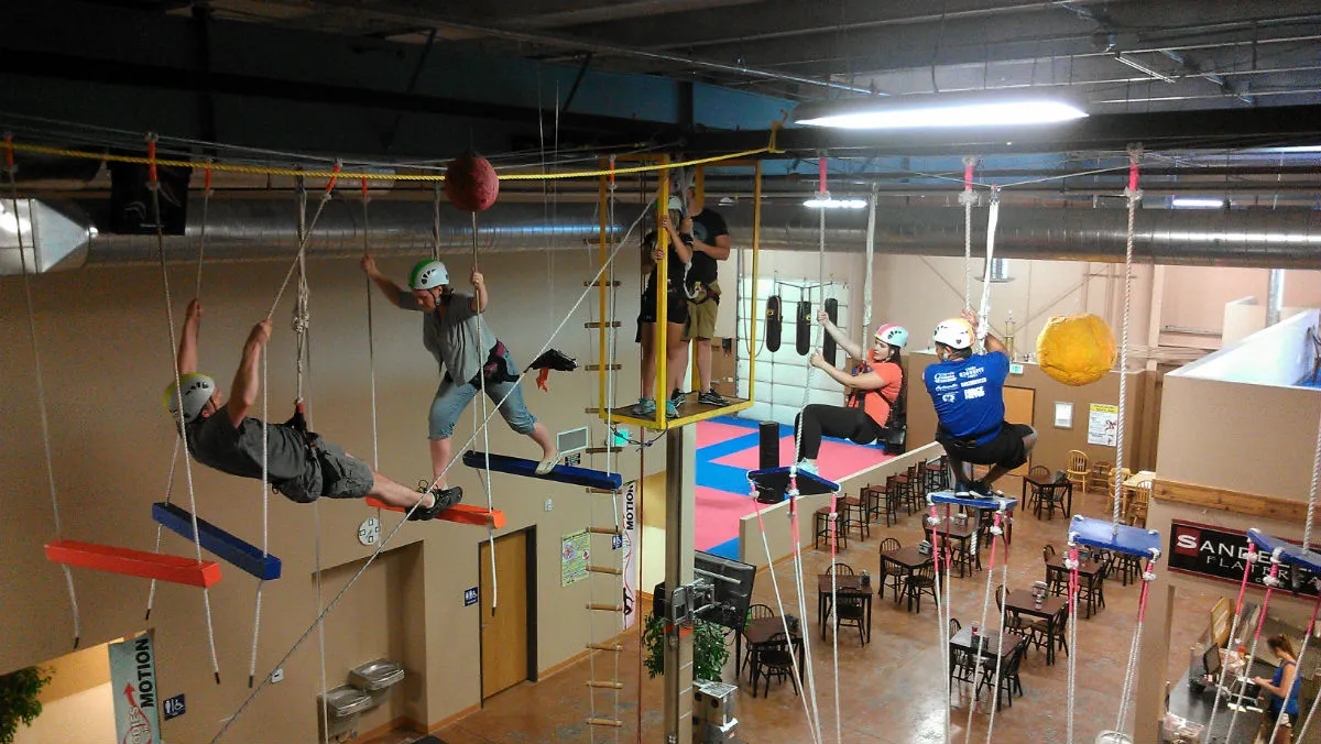Adults in harnesses on the indoor high ropes course