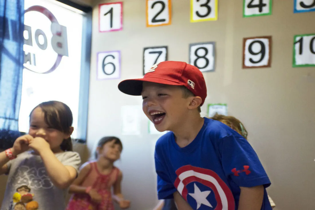 A laughing preschooler in a red cap