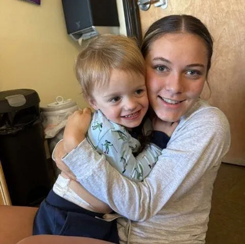 A teacher hugging a smiling toddler